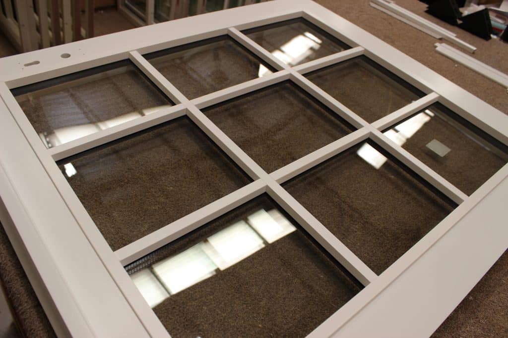 A white-framed window with glass panes featuring elegant astragal bars, enhancing its classic design.